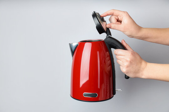 Woman with electric kettle on light grey background, closeup. Space for text