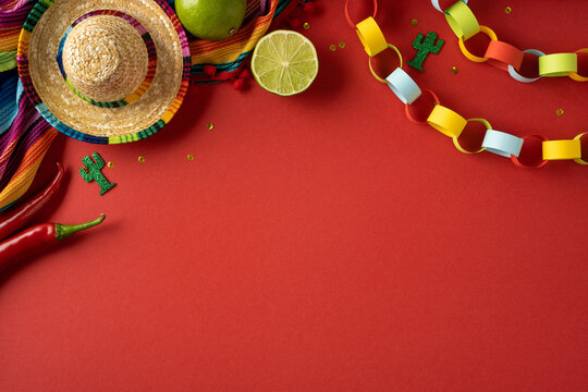 Cinco de Mayo fiesta flat lay with sombrero lime chili and colorful paper chain decorations