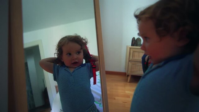 Toddler standing in front of mirror trying on bicycle helmet looking at reflection playful childhood moment of self discovery identity and curiosity inside home bedroom