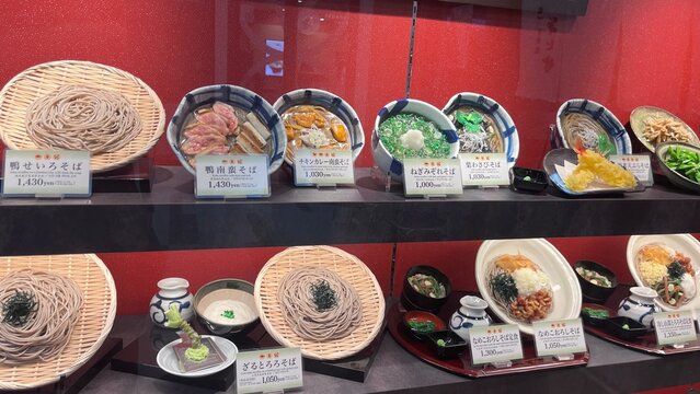 Japanese plastic food samples and window display featuring various soba noodle dishes like duck leek and tempura at Narita International Airport - Chiba, Japan, October 29, 2025