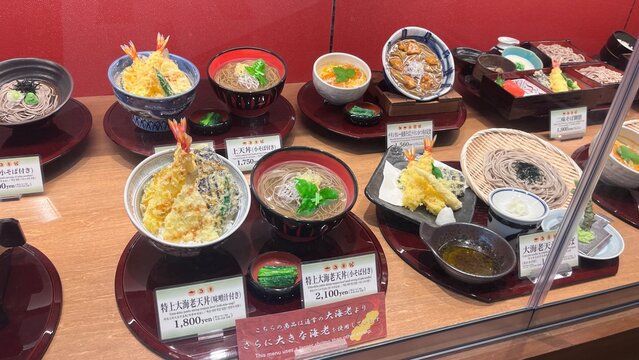 Realistic plastic food replicas of shrimp tempura bowls, soba noodles and Japanese sets displayed in a restaurant window at Narita International Airport - Chiba, Japan, October 29, 2025