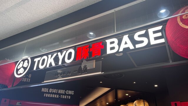 Tokyo Tonkotsu Base Made by Ippudo illuminated ramen restaurant storefront sign featuring red Tonkotsu kanji and paper lanterns at Narita Airport - Chiba, Japan, October 29, 2025