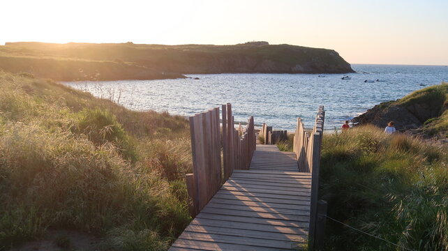 Escalier en bois descendant vers la plage de la Varde &agrave; Saint-Malo / Roth&eacute;neuf en Bretagne, paysage de c&ocirc;te et de mer avec vue sur la pointe de la Varde, au soleil couchant (France)
