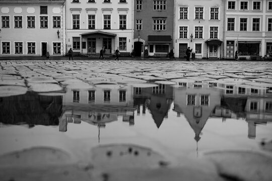 Black and white reflection of city buildings in a puddle