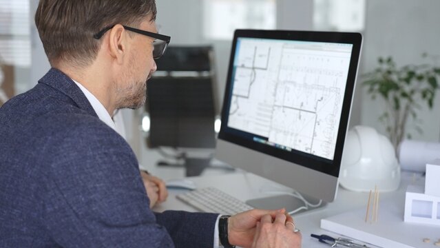 Architecture and engineering team collaborating on project blueprints using computer aided design software in an office. Business and architecture concept