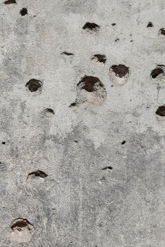 Old concrete wall riddled with bullet holes