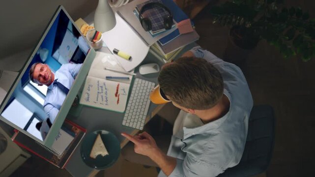 Remote colleagues calling web in evening home top view. Man videocalling late