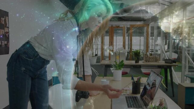 Supporting with hands, woman leaning over desk, reaching and editing while starfield overlay drifts