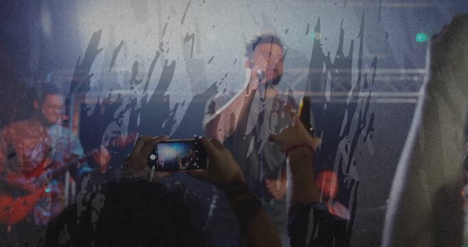 Fan raising phone and recording concert, lead singer singing, guitar visible, overlay obscuring
