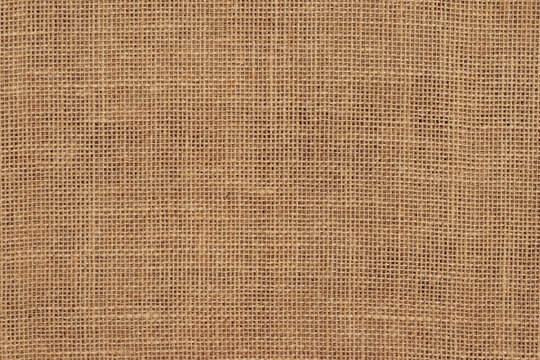 Brown burlap cloth background or sack cloth for packing. Natural linen threads texture. Sackcloth, empty space. Wrapping detail, old grainy cotton backdrop close-up.