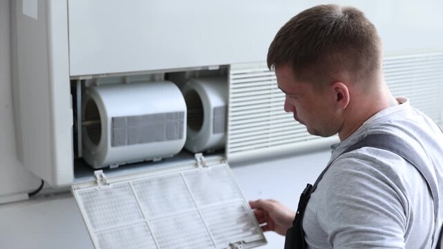 Professional technician cleaning modern air conditioner indoors