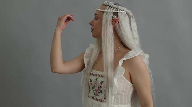 Beautiful girl dressed as elf on grey background, camera moving in