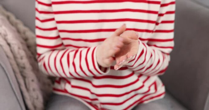 Woman clapping hands in armchair indoors, closeup