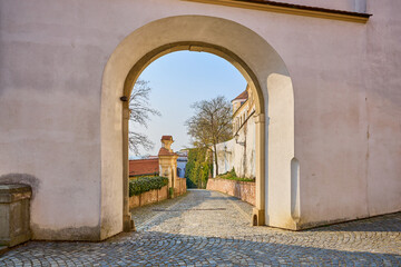 Naklejka premium Historic stone archway leading to quaint cobblestone pathway on a sunny day