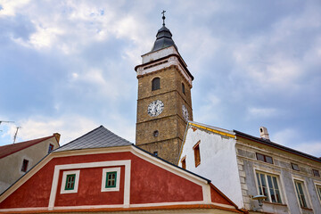 Fototapeta premium Historic clock tower and colorful buildings against cloudy sky