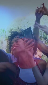 Woman raising phone and recording, causing animated icons and light trails, capturing festival joy