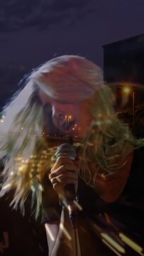 Vertical video: Raising tambourine lead singer with mic starting night lights blend adding mood