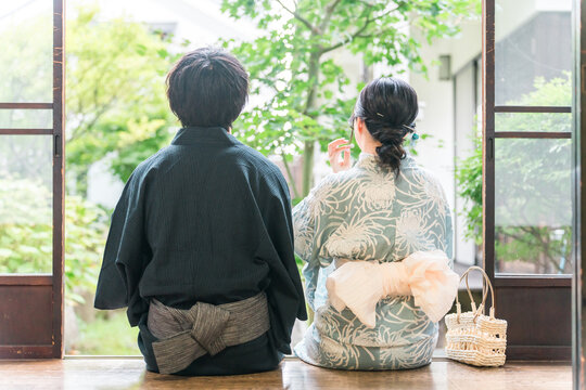 A couple in yukata (traditional Japanese summer kimono) relaxing on the veranda of a traditional Japanese house.