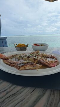 Fish in dish on the beach, tasty meal.  Vertical video.