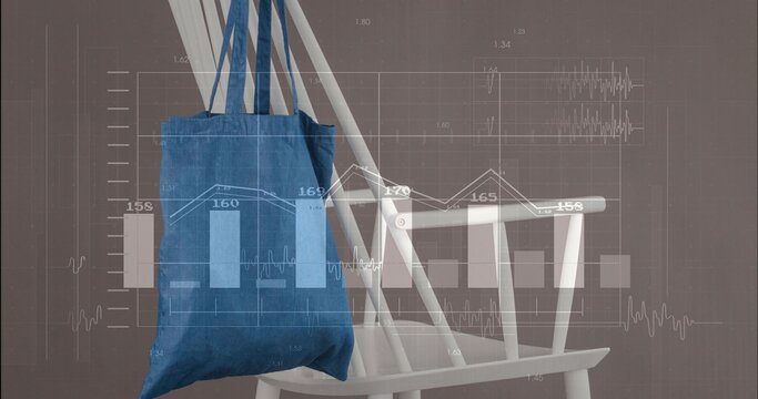 Hanging blue canvas tote bag showing straps over white wooden chair in studio, with data graphs