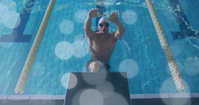 Male swimmer pressing block, launching into backstroke start for training, bokeh overlays obscuring