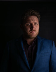 Obraz premium Suspicious expression portrait of man in suit looking sideways in dark lighting