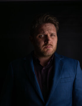 Suspicious expression portrait of man in suit looking sideways in dark lighting