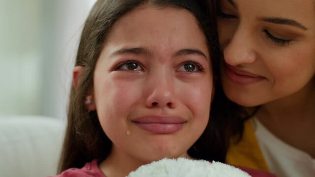 Loving caring Caucasian mother sister hug support calming sad little girl crying close up child woman female stress love parent embrace kid mom daughter cry at home indoors family relationship bonding