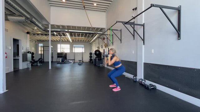 woman doing a goblet squat, lifting weights in gym