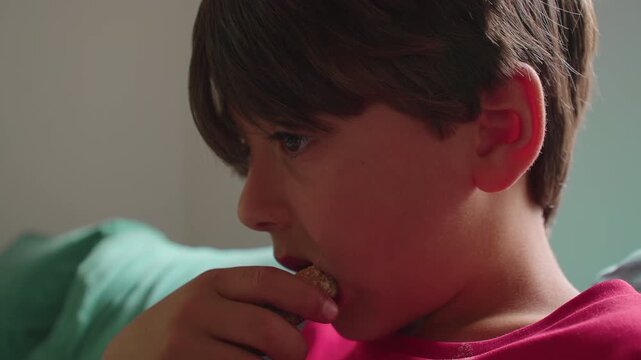 Young boy eating slice of bread with fruit jam during breakfast at home showing simple childhood meal moment and everyday family kitchen routine in domestic setting