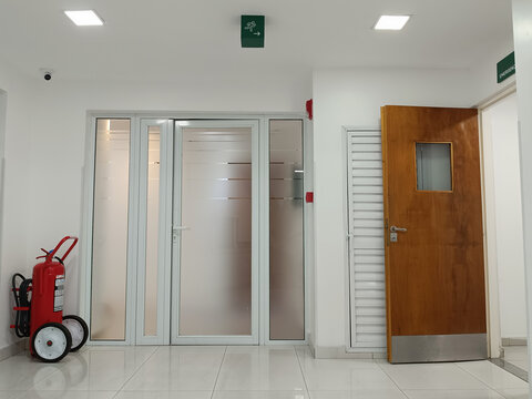 Clean hospital area with fire extinguisher and emergency exit.