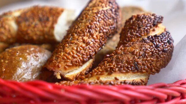 Freshly baked simit in a red basket, a traditional turkish bread with sesame seeds.