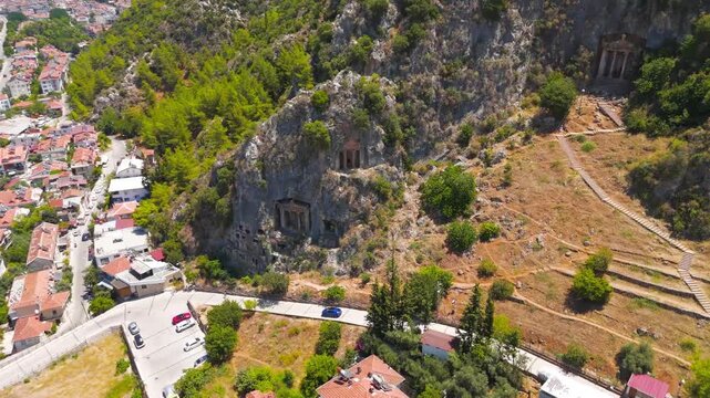 Fethiye, Turkey. Ancient Lycian rock cut tombs and temple tombs carved into the cliff face on a sunny summer day, aerial drone view.. Aerial View, Fly Forward