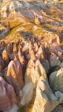 Vertical video. Goreme, Nevsehir, Turkey. Dreamlike landscape of Devrent Valley at sunset with whimsical stone figures and colorful geological patterns from above.. Aerial View, Departure of the came
