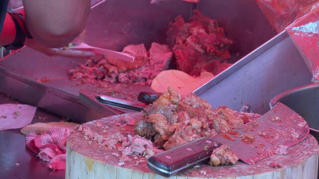 Authentic Mexican street food vendor chopping meat on a traditional wooden block, close-up, 4K ProRes.