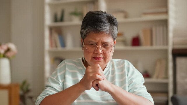 Elderly Asian woman in wheelchair looking out in living room, feeling lonely and missing freedom, retirement lifestyle change, emotional moment needing support, care, encouragement and family connecti