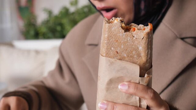 Woman enjoys meal in cozy cafe setting with food wrap