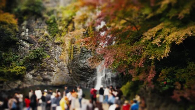 Miniature tilt-shift effect of tourists admiring waterfall
