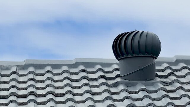 Industrial Metal Turbine Roof Ventilator Spinning on Gray Tiled Rooftop