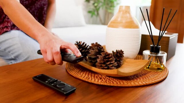 Person Placing Remote Controls on a Wooden Coffee Table in Living Room