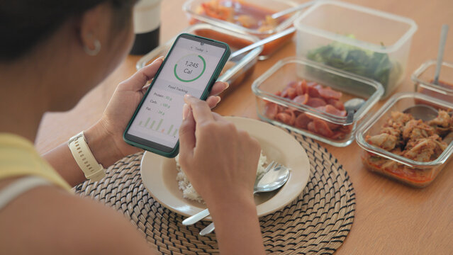 Young adult black asia people active gen z using AI phone record data daily meal tracker clean food diet app control. Asian Smart living care happy life goal routine plan lunch time home dining table.