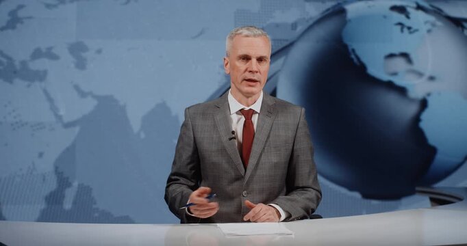 Professional Male Anchor in Grey Checkered Suit and Red Tie Looking at Camera and Gesturing. Concept of Popular Platforms For Discussing Stock Exchange, Market, and Financial News With Experts.