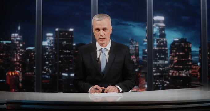 Confident Male Presenter in Formal Wear Discussing Social Issues, Looking at Camera and Gesturing With Pen, With Night City Background. Concept of Talk Show and Authoritative Public Discourse.