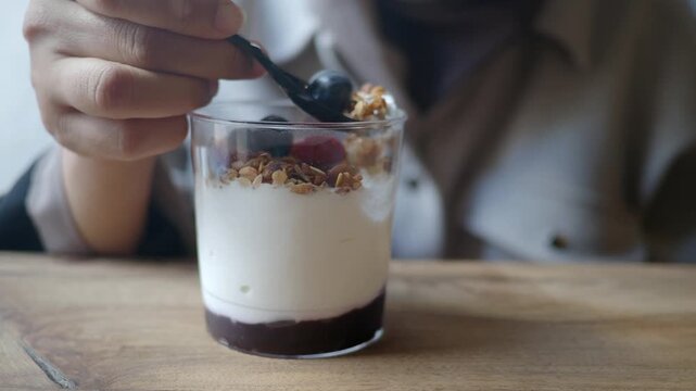 Woman enjoying healthy breakfast with yogurt, granola, and fresh berries.