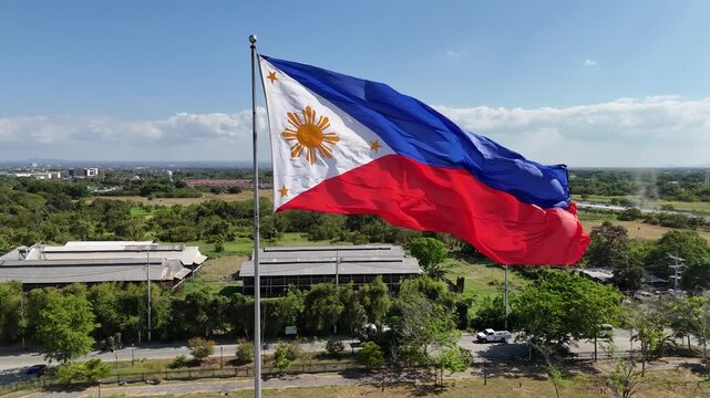 Aerial drone footage orbiting a huge Philippine Independence flag in Imus Heritage Park, Cavite, Philippines. Showcases national pride, historical landmark, and scenic park landscape. Ideal for travel