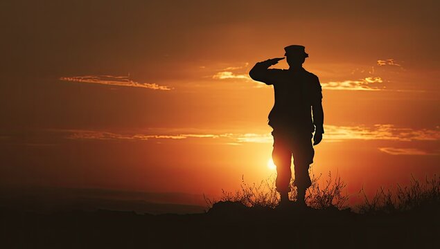 Solitary soldier saluting during a dramatic, fiery sunset