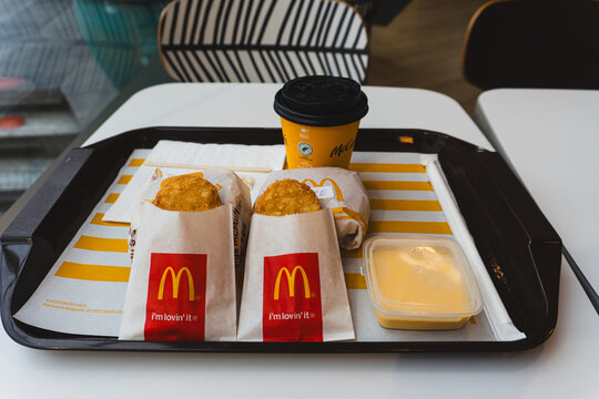 THAILAND - APRIL 4, 2026: A McDonald's breakfast meal on a tray featuring two hash browns, wrapped McMuffins, a McCafe coffee cup, and dipping sauce.