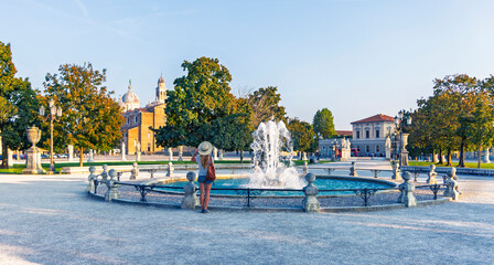 Tourist Woman Looking at a Beautiful Fountain in Prato della Valle Square at Golden Hour, Padua, Italy © M.studio