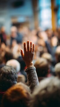A raised hand with a bracelet in a blurred crowd conveys a sense of participation in a US election or vote with a hopeful mood