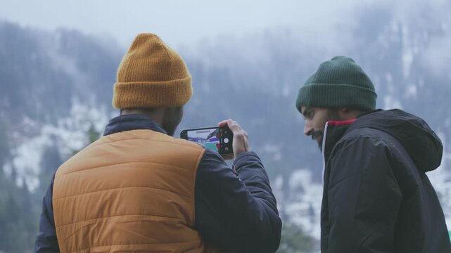 Two Men Taking Selfie on Snowy Mountain by River in Jammu and Kashmir, India